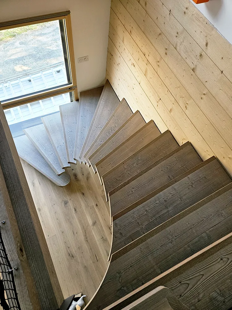Escalier tournant en bois sur mesure vu du dessus avec design fluide et marches massives
